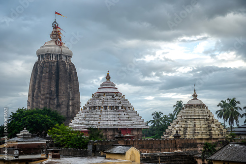 Rath yatra and jagannath ratha yatra temple complex under dramatic monsoon clouds with ancient towers palm trees sacred pilgrimage atmosphere in puri