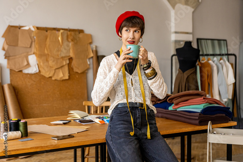 Young woman in red beret having coffee in a fashion design studio