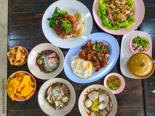 A dining table filled with authentic Thai dishes, including noodles, rice, and a variety of traditional foods, ready to enjoy.