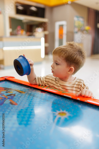 Photography Cute little boy playing air hockey game at amusement center