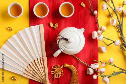 Foto Traditional tea with paper fan and Chinese symbols on yellow background