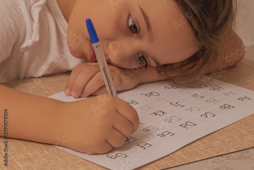 Fotografie Horizontal close up shot of a child holding a pen and practicing writing english