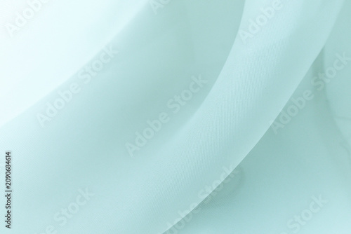 Soft delicate transparent organza, chiffon, silk fabric in seafoam green. Close up folds of fabric textile texture as background in aqua green color with copy space.