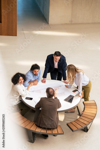 Multiracial business colleagues planning strategy at table in corridor
