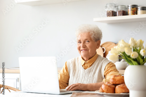 Senior woman using laptop a...