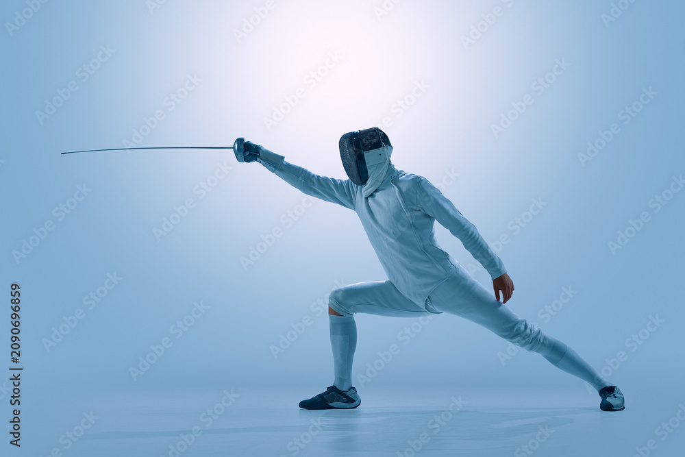 Fototapeta premium Male fencer performing powerful attacking lunge with epee in modern studio. Concept of competitive fencing, precision movement, tactical attack, athletic discipline, and individual performance.