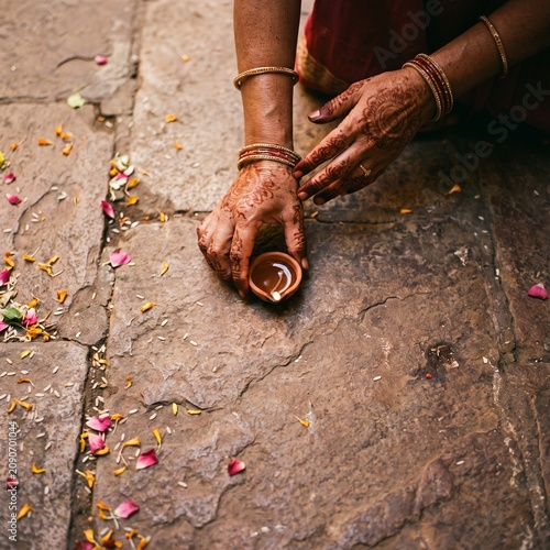 Woman's Henna Hands Placing Clay Diya on Stone
