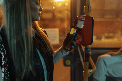 Foto Woman paying bus fare using smartphone contactless