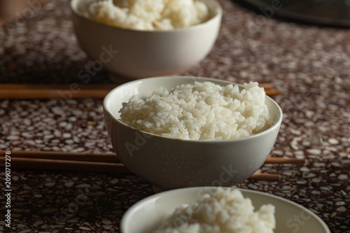 A bowl of steaming white rice on a stone table, a simple and authentic image of daily family meals in Vietnam