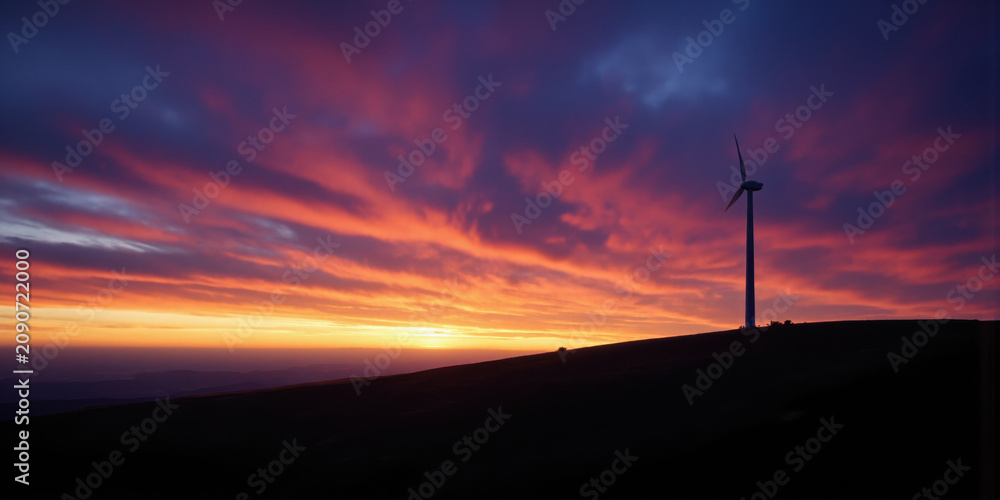 Obraz premium Wind Turbine Silhouette at Dawn Lone turbine on a hill outlined against a gradient sky transitioning from deep violet to