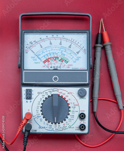 Fotografie Analog Multimeter with Test Probes on Red Background - Electrical Measuring Inst