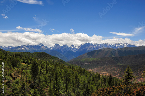 Breathtaking mountain range with lush green forests under clear blue sky
