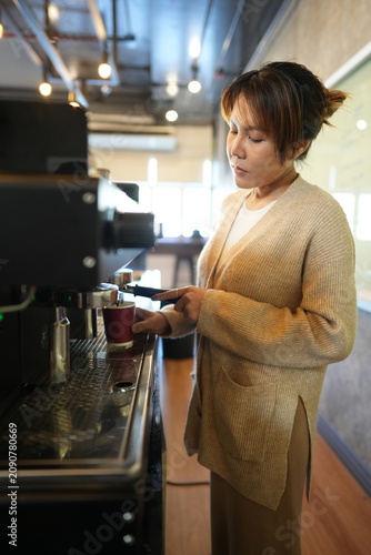 Fotografie Young barista tamping fresh coffee levels and tamps the coffee dose at the espre