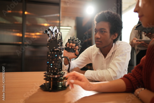 Foto Student and classmate with a robotic hand reaches toward the illuminated robotic