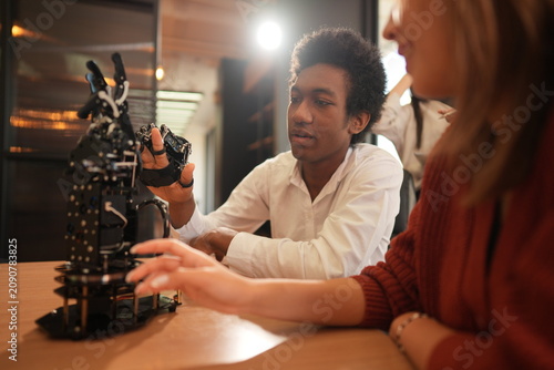 Fotografie Student and classmate with a robotic hand discusses the robotic hand with a clas