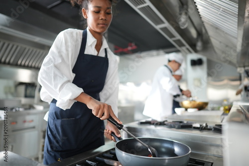 Canvastavla Young female culinary student cooking cooks at the stainless steel range in a ch