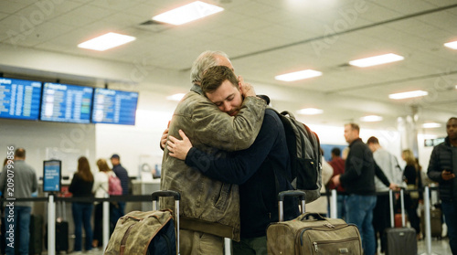 Elderly Father Embracing Adult Son at Airport Departure Gate in Emotional Farewell Hug