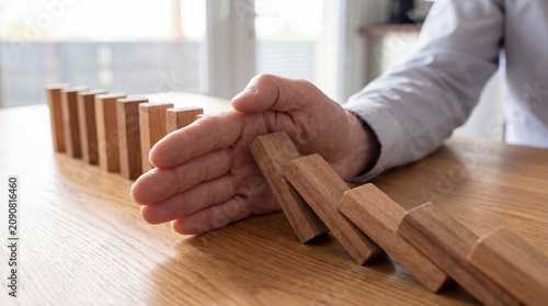 Hand Protecting Wooden Domino Chain Reaction for Business Risk Management Concept