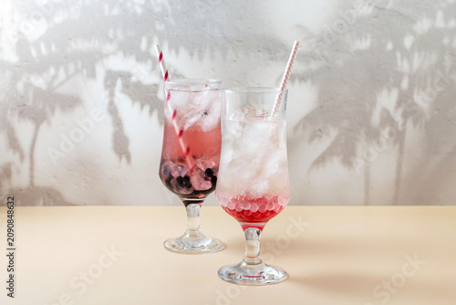 Two glasses of lemonade with ice, tapioca balls and berry syrup