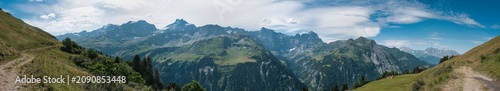 Large panorama of the Schächen Valley in the canton of Uri in summer with a blue sky and white clouds.