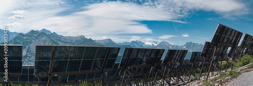 Canvastavla Large panorama of alpine solar panels in the Schächental valley in the canton of Uri in summer under a blue sky with white clouds