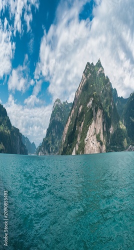 Large panorama from Lake Uri with Sisikon and Flüelen under a blue sky with white clouds.