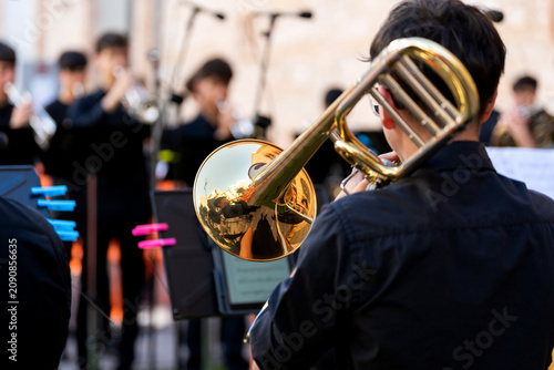 Foto Young musician playing trombone with brass band in outdoor street concert
