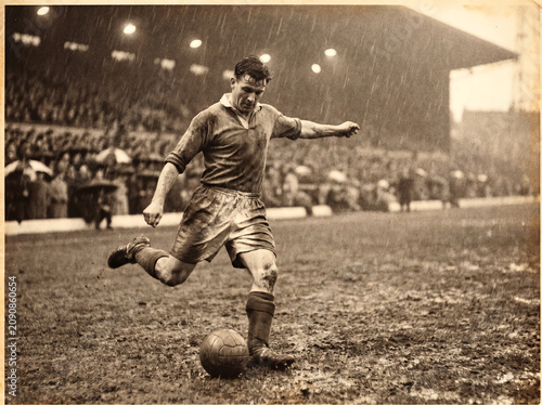 Vintage Action Shot of Footballer Kicking Ball in Heavy Rain