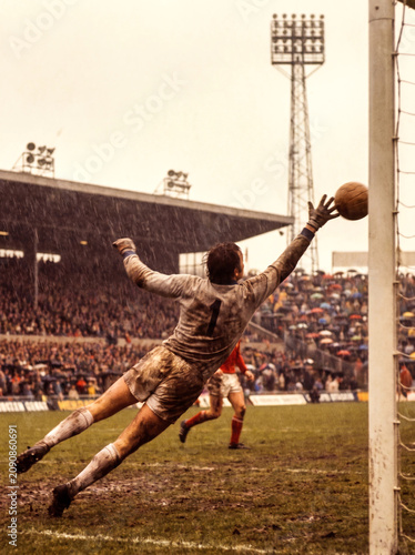 Vintage Muddy Soccer Goalkeeper Diving for a Save in Rain
