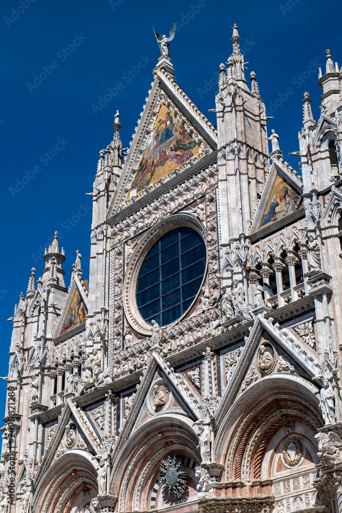 Fototapeta premium Close-up of Siena Cathedral’s intricate facade with rose window and decorative stonework. The image showcases the richness of medieval religious architecture.