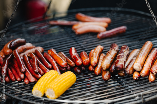 Golden, fatty fried sausages and corn on a large barbecue grill