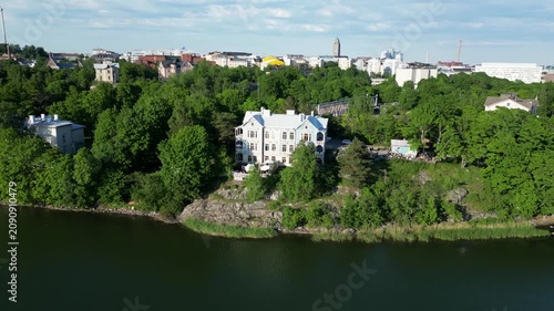 Aerial drone view of Art Cafe Terrace located by Töölönlahti Bay in Helsinki, Finland. Beautiful urban waterfront scenery featuring the café terrace, surrounding nature, and Finnish cityscape content.