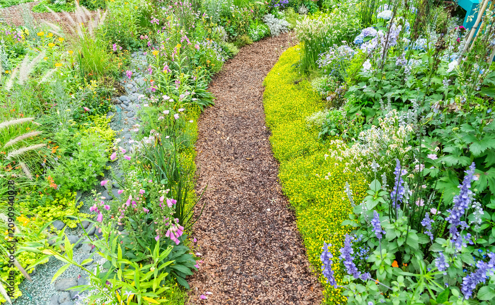 Naklejka premium colorful flowers with rock path leading through a flower garden