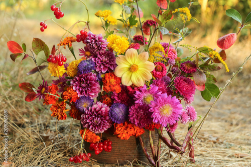 Beautiful autumn bouquet with dahlia, aster, marigold flower and colorful leaves. Fall pink yellow orange red purple flowers close up