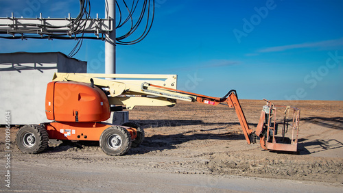 Foto A self-propelled telescopic tower is parked on a dirt path near a construction site