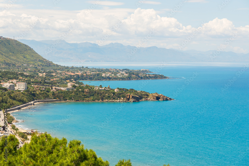 Naklejka premium Panoramic aerial view of a coastal resort town nestled against green hills and the sea