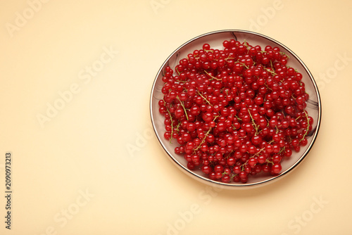 Red currants on plate on beige background. Fresh and vibrant food photography for healthy eating.