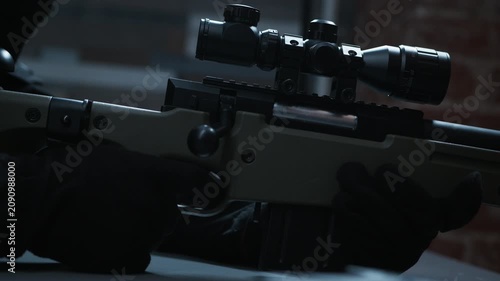 Cinematic side view of a scoped bolt-action sniper rifle resting in a dark, moody interior with brick walls behind.