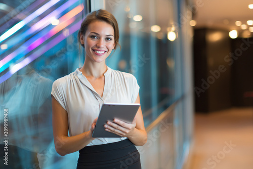Young attractive businesswoman CEO, elegant skirt, holding premium tablet, executive board meeting, collaborative workforce, premium corporate portrait.