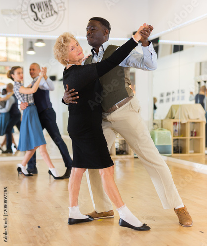 Man and senior woman dancing waltz in studio