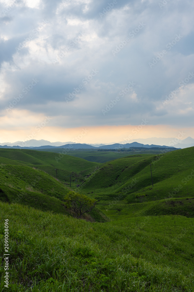 Fototapeta premium Sunset View of Orange Sky and Rolling Hills Along Aso Milk Road, Kumamoto, Japan