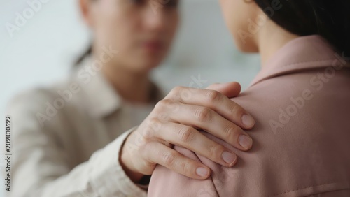A supportive person placing a hand on another person shoulder to show deep comfort