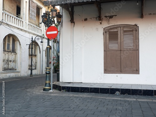 Exterior view of an empty stone paved pedestrian walkway flanked by classic heritage buildings with wooden shutters.