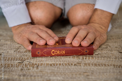 Man kneeling, his hands resting on the holy coran book during prayer