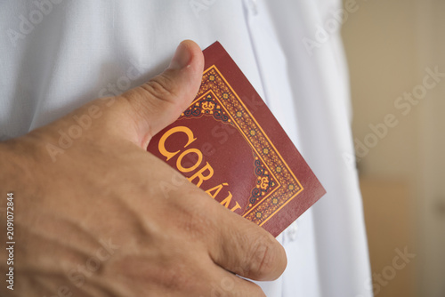 Hand holding the holy quran, representing islamic faith and spirituality