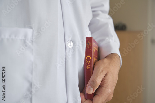 Muslim person carrying a copy of the holy book coran