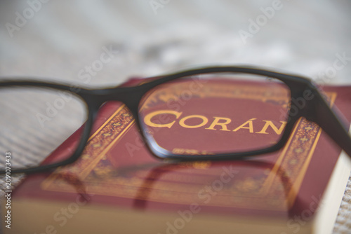 Eyeglasses resting on a red coran book, symbolizing spiritual study and faith
