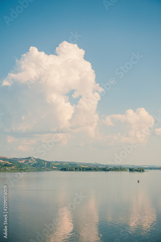 Scenic river reflects blue cloudy sky. Peaceful landscape