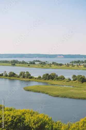 Natural scene with tranquil river meanders through green field and open marsh