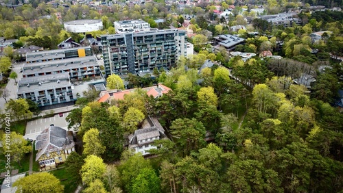 Aerial view of Palanga, Lithuania reveals a blend of urban and natural landscapes. Central high-rise structures with modern architecture are surrounded by dense forests and residential buildings